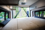 Cozy rv rental interior: spacious bed, open rear doors with screen, offering forest views. Relax and connect with nature.