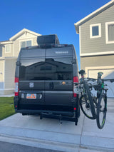Grey Winnebago Solis **RV rental** van with bikes on a rear rack, parked in a driveway. Utah license plate visible.