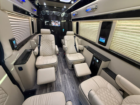 Plush RV rental interior: cream leather captain's chairs, footrests, smart controls, and entertainment for luxury travel.