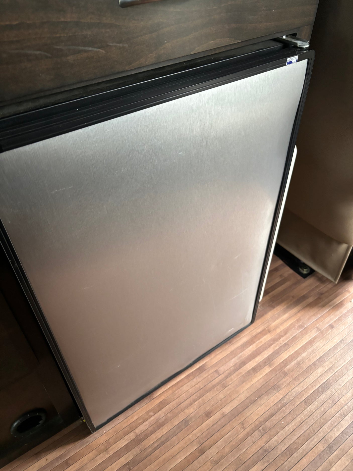 Compact Norcold stainless steel refrigerator with minor scratches in an RV rental for your travels.