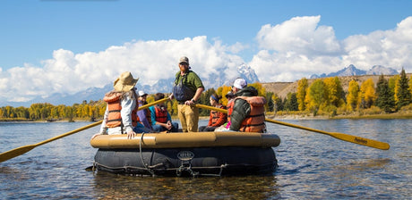 Scenic river rafting on a sunny day with mountains and fall foliage. A perfect outdoor adventure for your RV rental vacation.