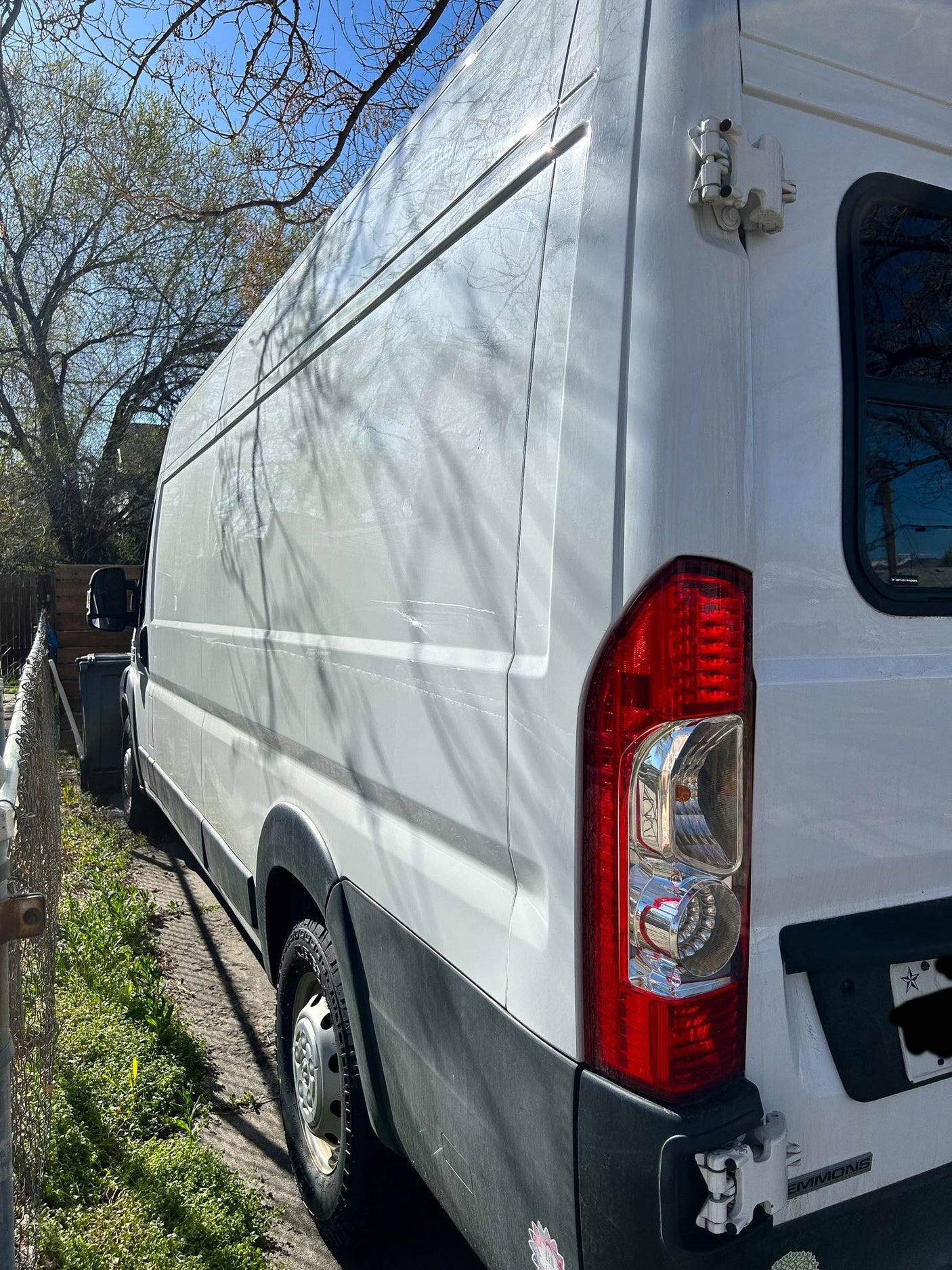 White RV rental van, parked outdoors with tree shadows on its side and rear.
