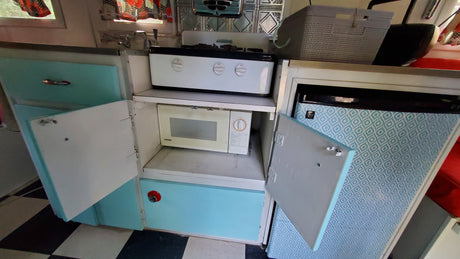 RV rental kitchen: White stovetop, Samsung microwave, light blue cabinets, and patterned fridge area. Functional and compact.