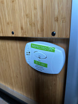 White First Alert Carbon Monoxide Alarm on a wood wall, showing 'INSPECTED ON: 5-1-23', a key safety feature in an RV rental.