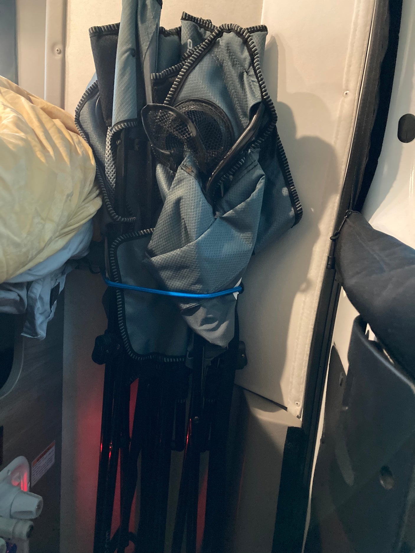 Folded gray camping chair secured inside an RV rental, showcasing compact storage solutions for travel gear.
