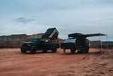 Explore with an RV rental: Black Jeep Gladiator, roof-top tent, & Escapod trailer set up for overlanding in the desert.