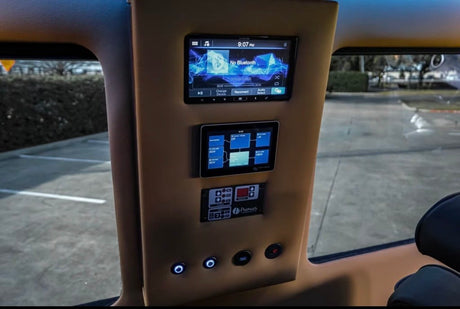 RV rental control panel: displays for entertainment (Bluetooth off), electrical power management, and system buttons. View of parking lot outside.