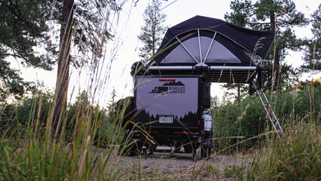 Overland camper trailer with rooftop tent deployed, perfect for an RV rental adventure into nature's off-grid beauty.