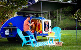 An RV rental provides the perfect camping trip. A couple relaxes with drinks by their blue teardrop camper under its awning.