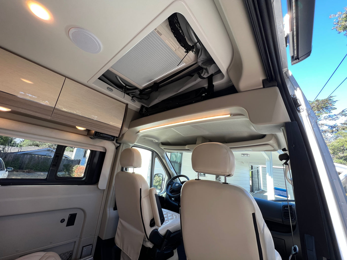 Modern RV rental interior with swivel seats, overhead cabinets, and roof vent, perfect for travel.