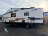 A clean white Forest River Vibe travel trailer, perfect for an RV rental, parked on gravel with power connected.