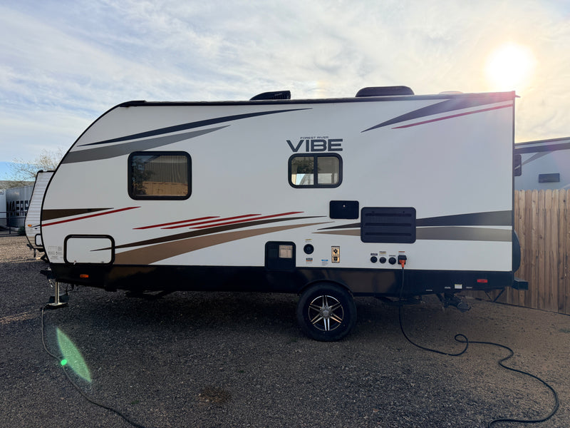 A clean white Forest River Vibe travel trailer, perfect for an RV rental, parked on gravel with power connected. — photo 15