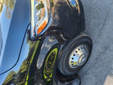 This black Mercedes-Benz van, a potential rv rental, features a sharp headlight and shiny wheel, reflecting trees and sky.