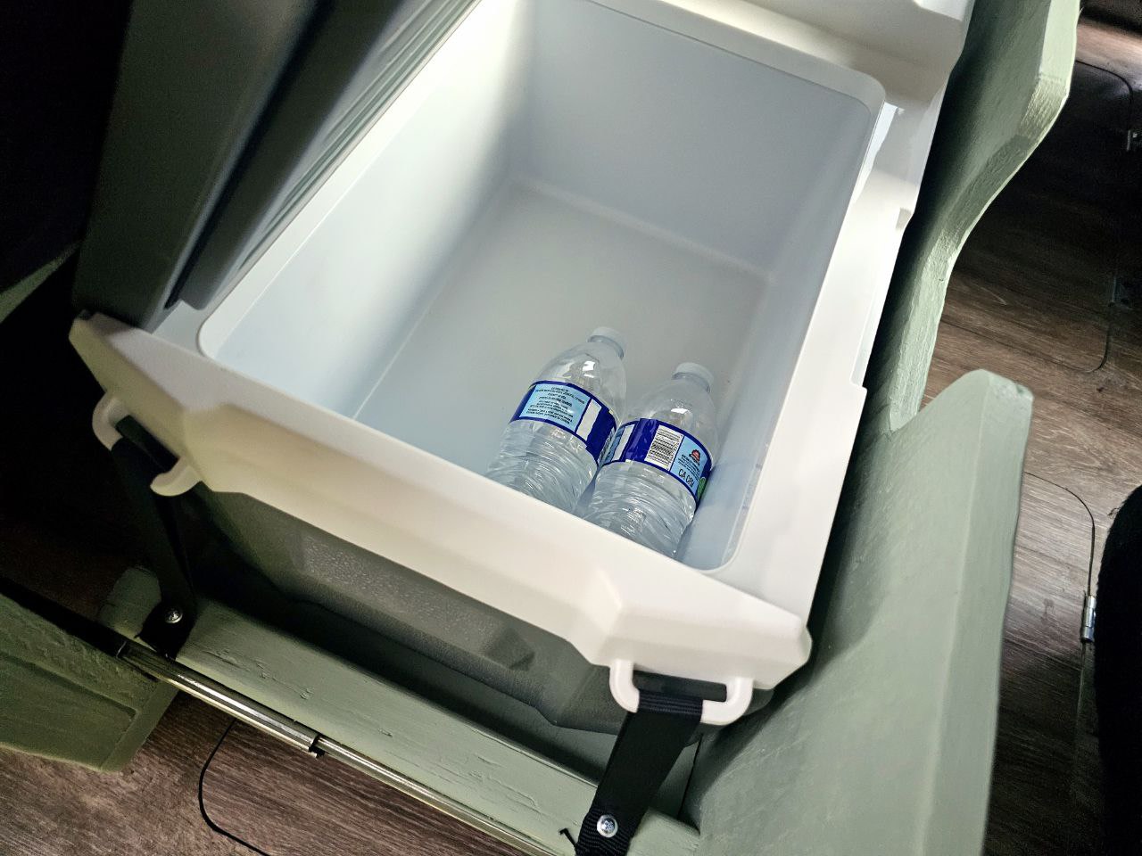 An open cooler with two water bottles, a key amenity in this RV rental, placed on wood flooring. — photo 8