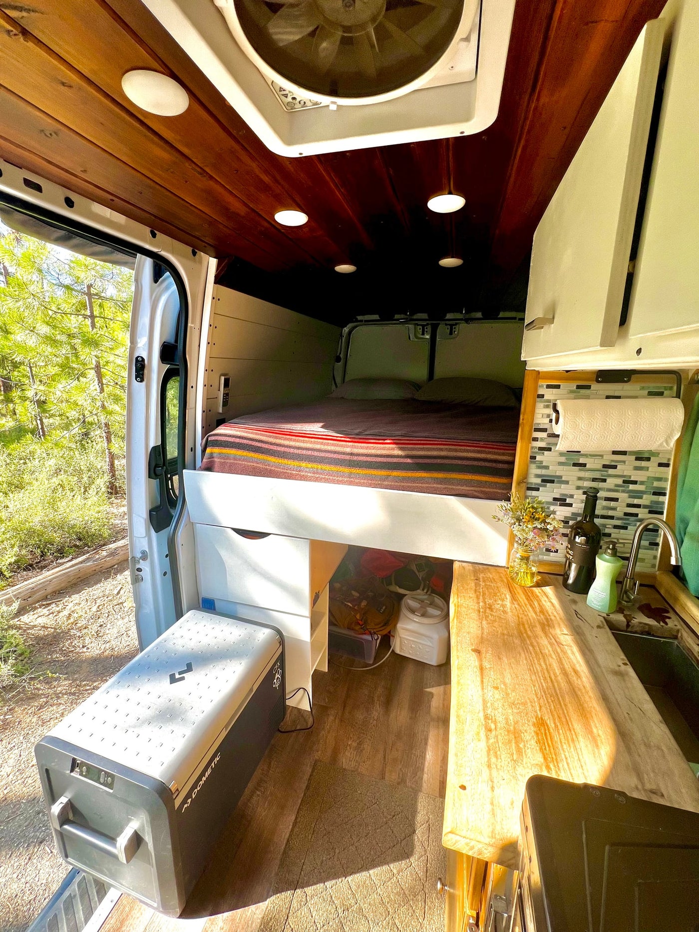 Cozy RV rental interior: bed, kitchen, Dometic cooler. Perfect for van life adventures surrounded by nature. — photo 8