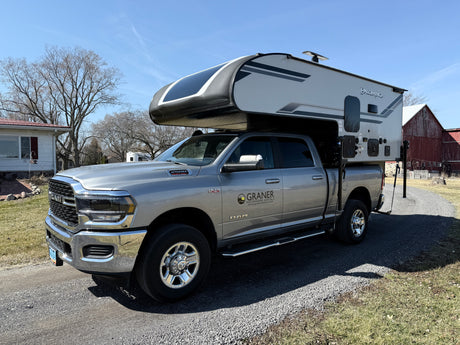 A silver RAM pickup with a Palomino truck camper, from Graner RV rental, ready for outdoor adventures.