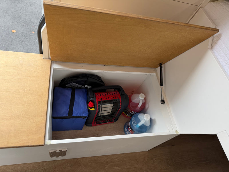 RV rental interior storage: portable heater, cooler bag, and utility liquids neatly stowed in a camper van compartment. — photo 20