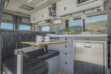 This RV rental camper van interior features a compact kitchen, dining space, and scenic mountain views for adventure.