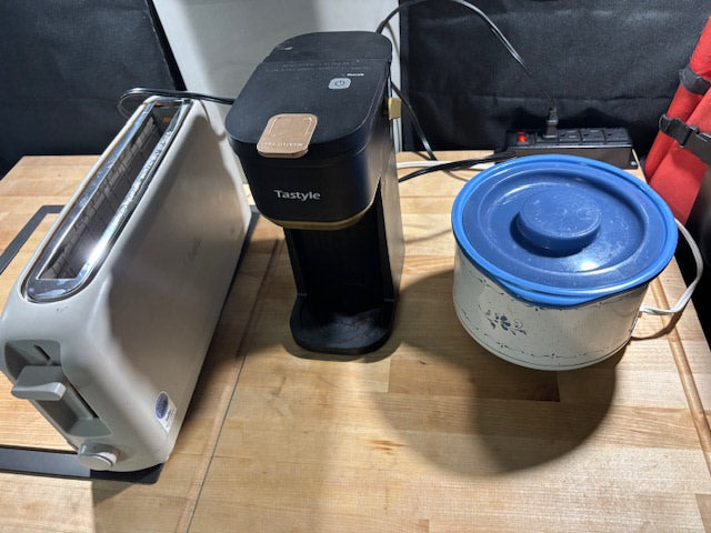Compact kitchen essentials for your RV rental: a toaster, coffee maker, and slow cooker on a wooden counter.
