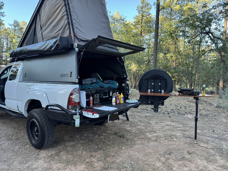Overland-ready RV rental, white truck with pop-top camper & outdoor kitchen setup at a wooded campsite. — photo 14