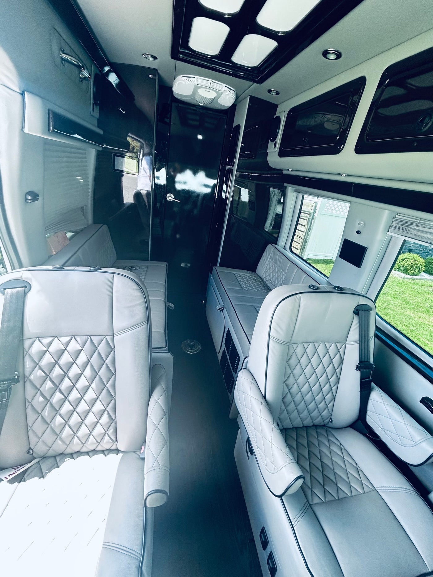 Inside this premium rv rental: Light gray diamond-stitched seats, dark wood flooring, and sleek overhead storage in a custom van. — photo 8