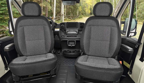 RV rental interior: Front cabin shows two grey fabric seats, a modern dashboard, and a beautiful forest road view.