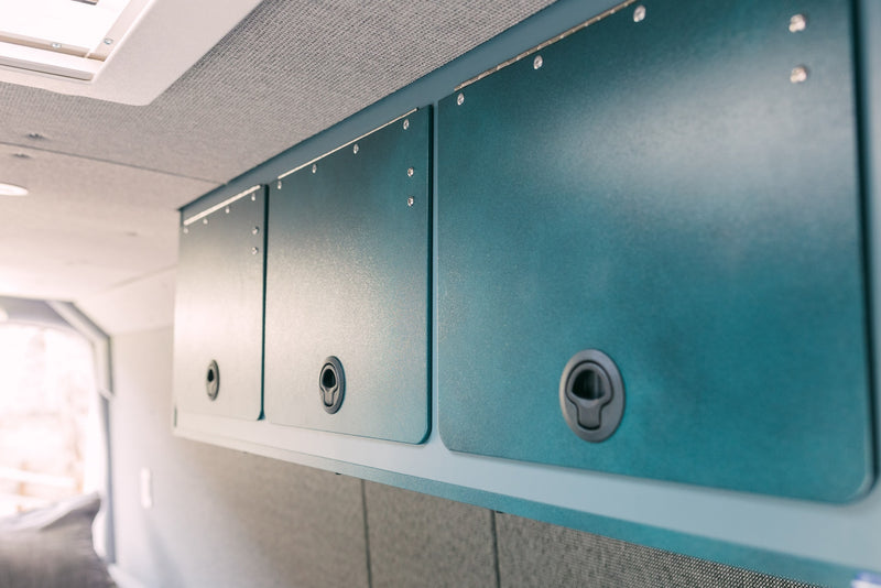 Close-up of stylish teal overhead cabinets with secure latches in an RV rental's modern interior. — photo 15