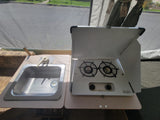 RV rental pop-up camper interior: a compact kitchen with a shiny stainless steel sink and an open two-burner stove.