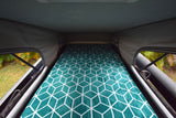 Comfortable pop-top bed in an RV rental, featuring a teal geometric pattern. Ideal for camper van adventures.