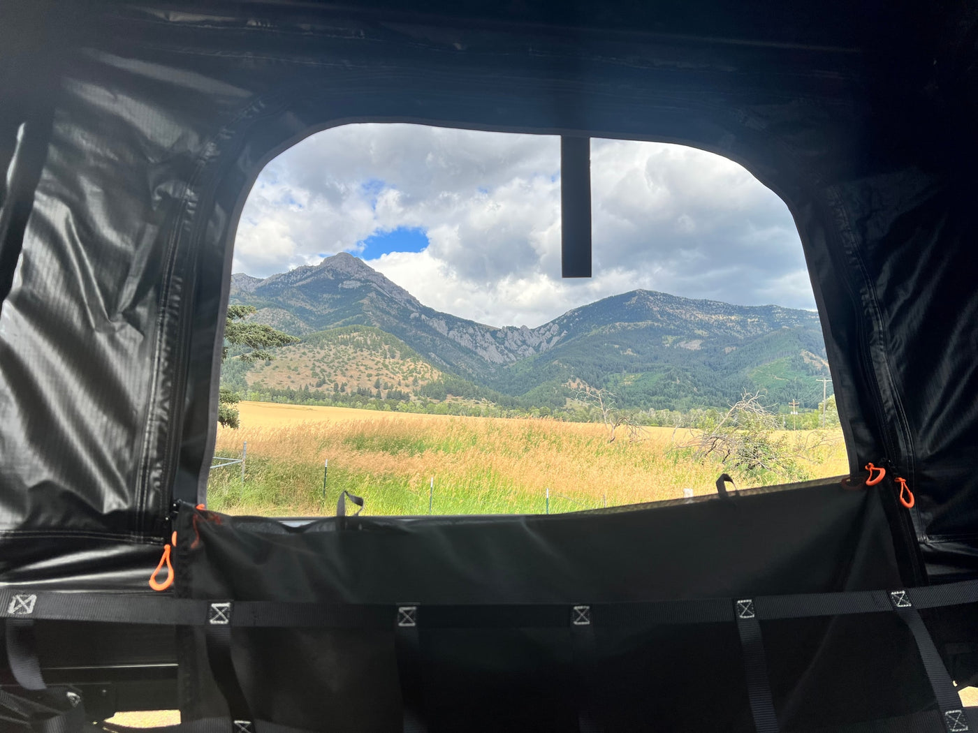 Inside an RV rental rooftop tent, enjoy a scenic mountain view over golden fields and distant hills. Perfect for camping! — photo 17
