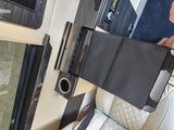Luxurious RV rental interior with cream leather seats, dark wood accents, and a control panel next to a flat black surface.