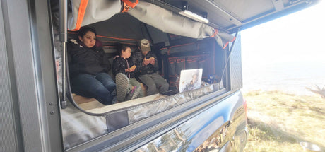 Family inside an RV rental truck camper, eating and relaxing with an ocean view. Comfortable camping travel.