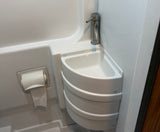 Compact RV rental bathroom featuring a corner sink, sleek faucet, and mounted toilet paper holder in a small, functional space.