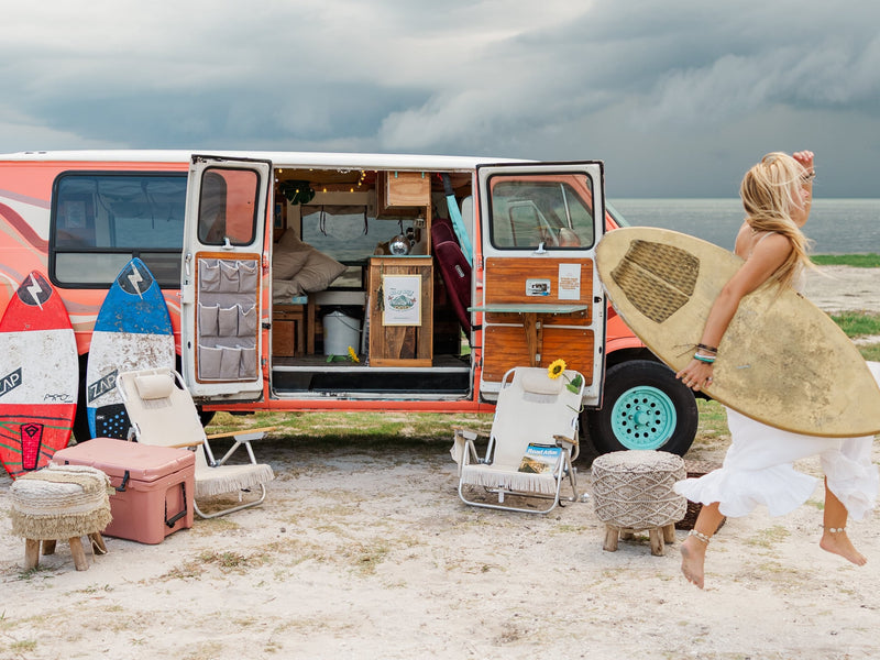  chairs & a personalized interior ready for adventure.|This rv rental sets the scene for adventure! A woman relaxes atop a retro van with surfboards — photo 3