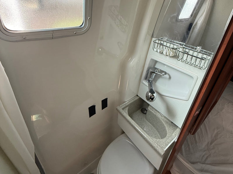  ready for comfortable travel.|Cozy rv rental interior: kitchen with sink & bed in a compact camper van. Wooden cabinets and window blinds visible.|RV interior: cozy bed — photo 17