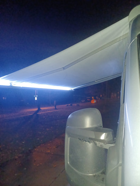 Night view from an RV rental: a bright LED-lit awning and side mirror. Great for evening camping.