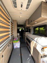 Cozy rv rental interior featuring a compact kitchen, bed, and ample storage, perfect for your next adventure.