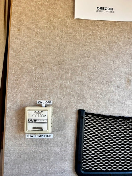 RV rental control unit on a textured wall: ON/OFF switch, thermostat with LOW TEMP HIGH settings, and an 'Oregon' sign.