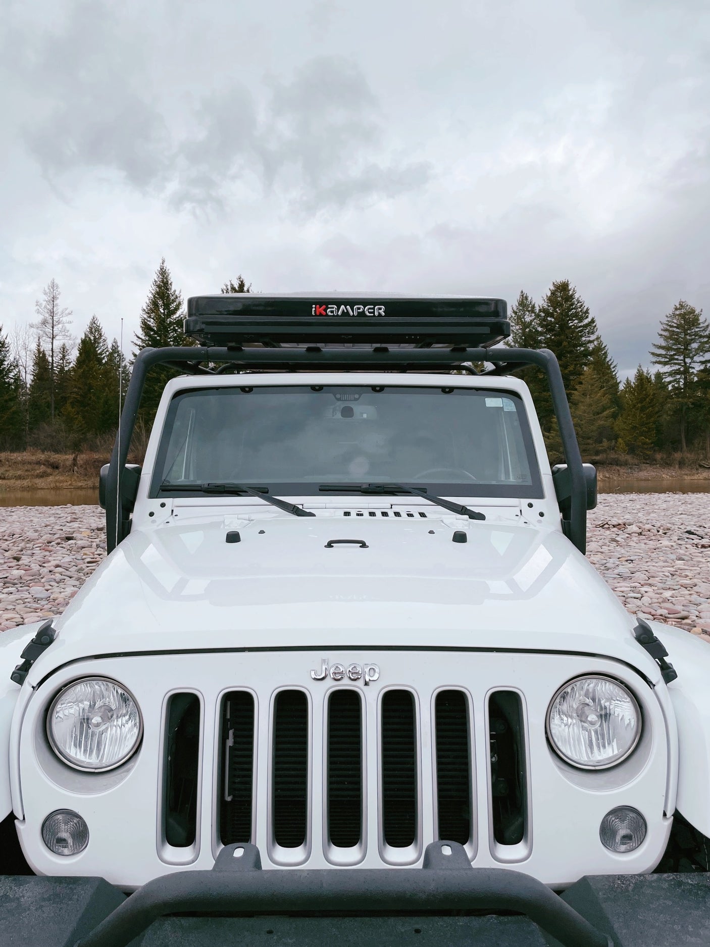 Front view of a white Jeep Wrangler with an iKamper rooftop tent, an ideal RV rental for off-grid nature adventures.