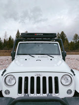 Front view of a white Jeep Wrangler with an iKamper rooftop tent, an ideal RV rental for off-grid nature adventures.