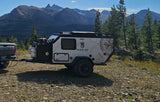 A sleek Mission Overland trailer, ideal for an RV rental adventure, parked on a rugged mountain trail. Ready for off-grid exploration.