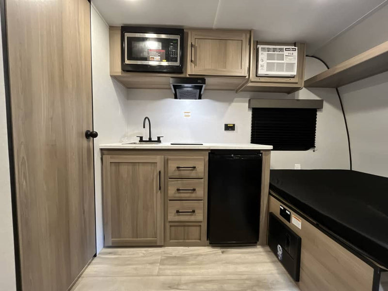  parked outdoors.|RV rental floor plan: Top-down view of a compact camper with bed — photo 8