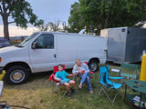 Camping setup with a white utility van and trailer, suitable for an RV rental adventure.