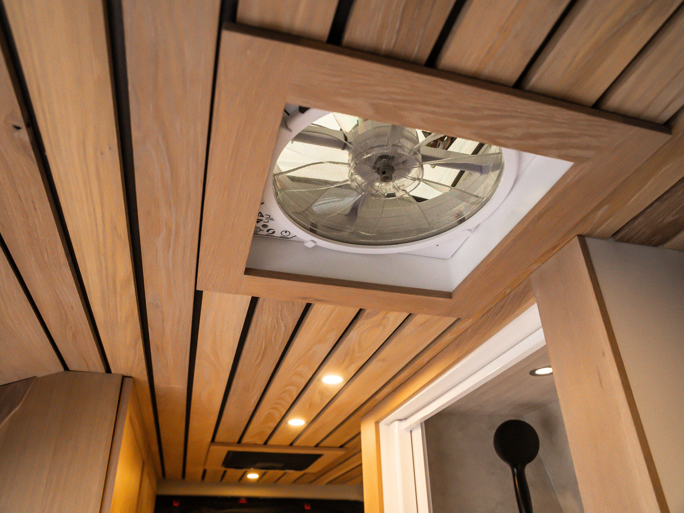 The warm wood-slat ceiling of this RV rental features a central vent fan and recessed lighting, enhancing comfort inside.