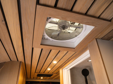 The warm wood-slat ceiling of this RV rental features a central vent fan and recessed lighting, enhancing comfort inside.