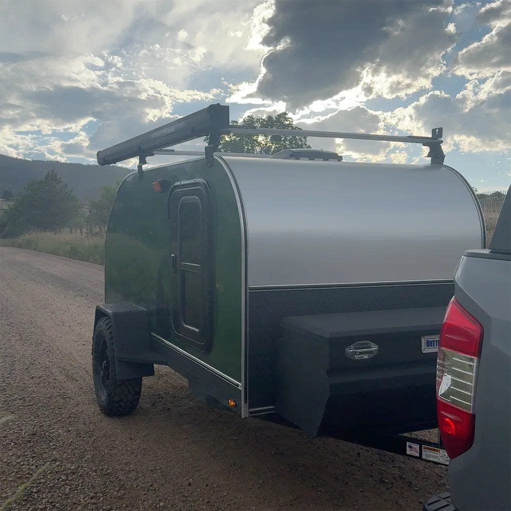 This green teardrop camper, perfect for RV rental adventures, is ready for off-road travel on a dirt road under a cloudy sky. — photo 2