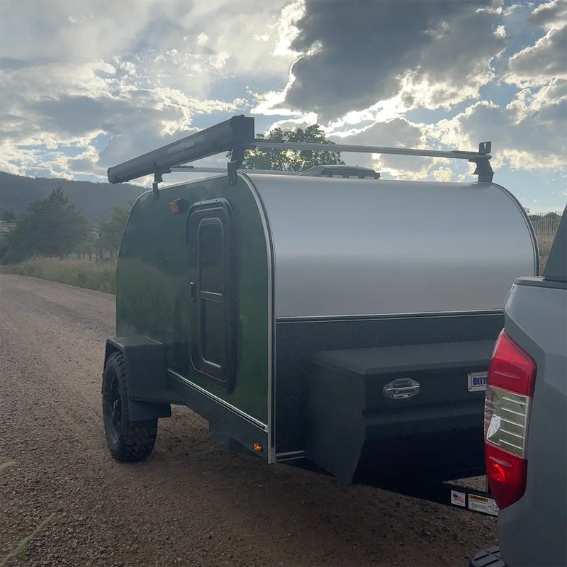 This green teardrop camper, perfect for RV rental adventures, is ready for off-road travel on a dirt road under a cloudy sky. — photo 2