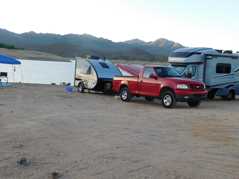 RV rental vehicles: Red pickup towing a Grand Ascape camper, and a Tiffin motorhome, parked by a lake and mountains. — photo 11