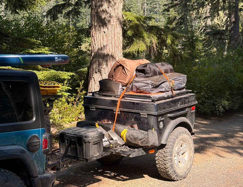 This off-road camping setup, featuring a Jeep, trailer, paddleboard & gear, offers outdoor adventure like an rv rental. — photo 1