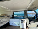Experience coastal living in this cozy RV rental with a stunning ocean view from inside your camper van bed & kitchen.